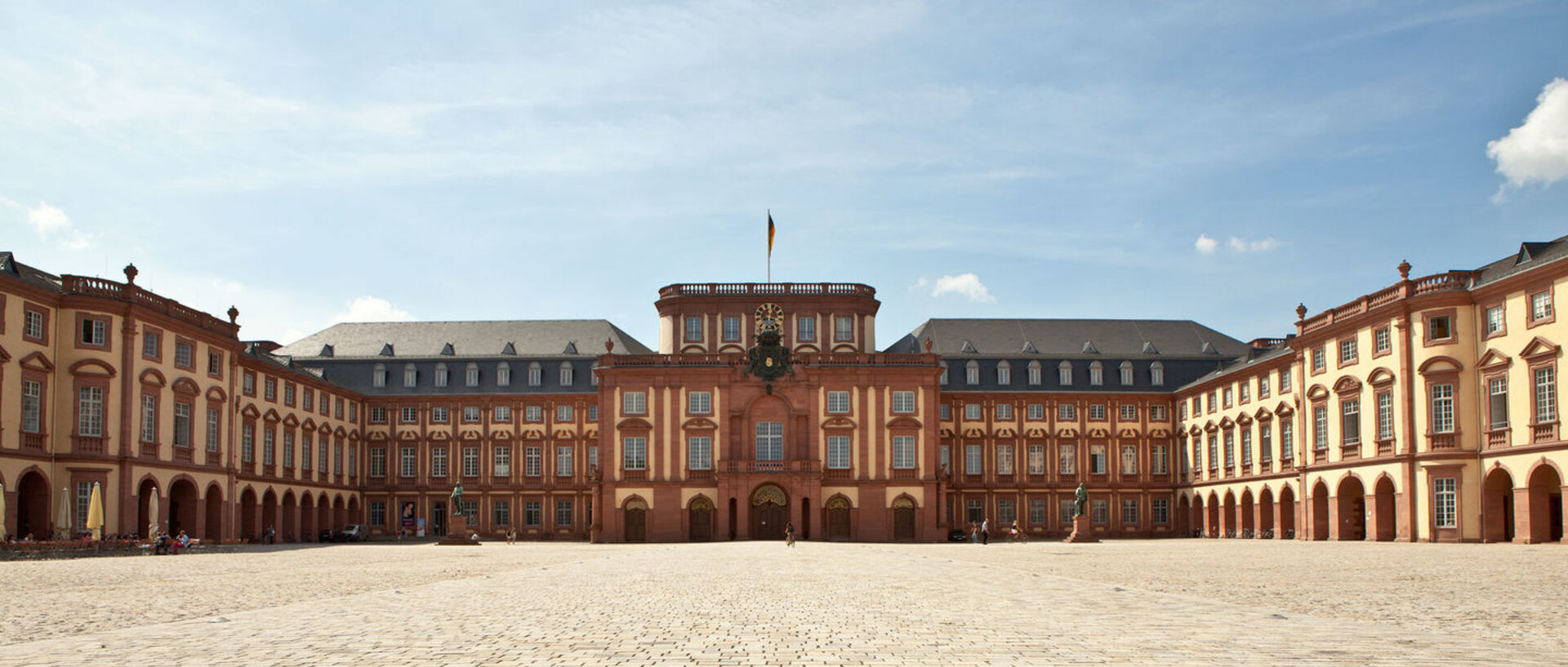 Das Mannheimer Barockschloss und der Ehrenhof unter blauem Himmel.