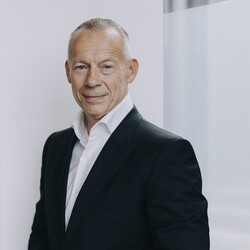 Walter Sinn trägt ein weißes Hemd und schwarzes Sakko