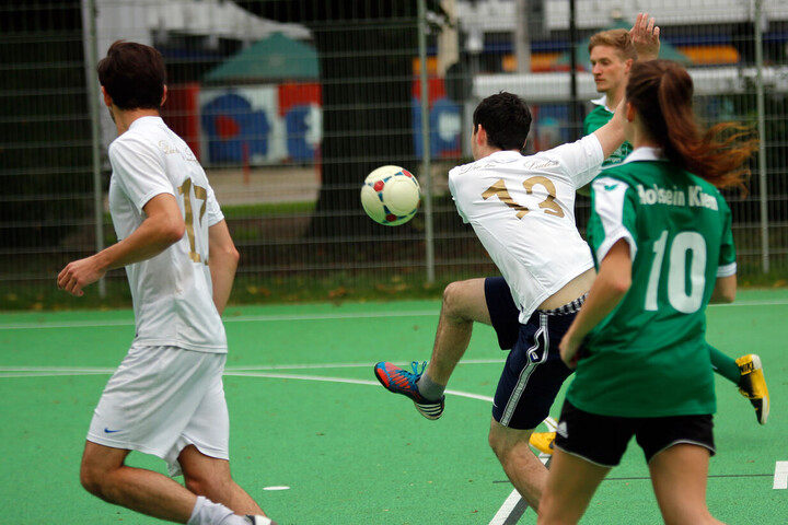 mehrere Personen spilen Fußball auf einem Sportplatz