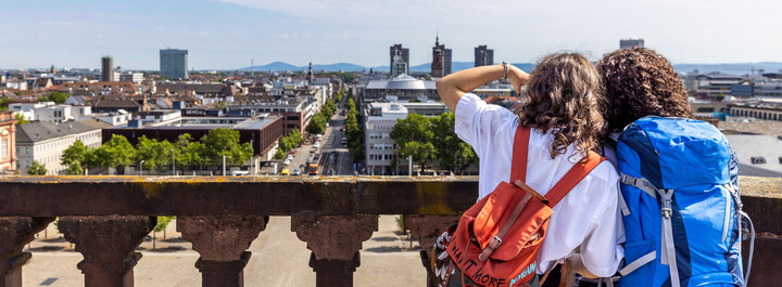 Zwei Studentinnen, von hinten zu sehen, stehen auf dem Balkon des Mannheimer Schlosses und schauen auf die Stadt.
