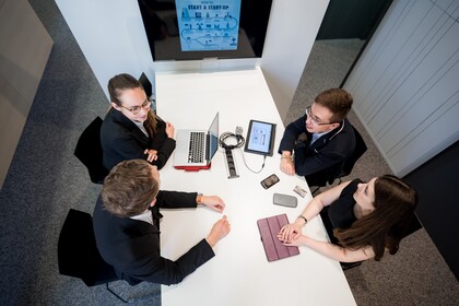 Studierende mit Lernmaterialien sitzen um Tisch