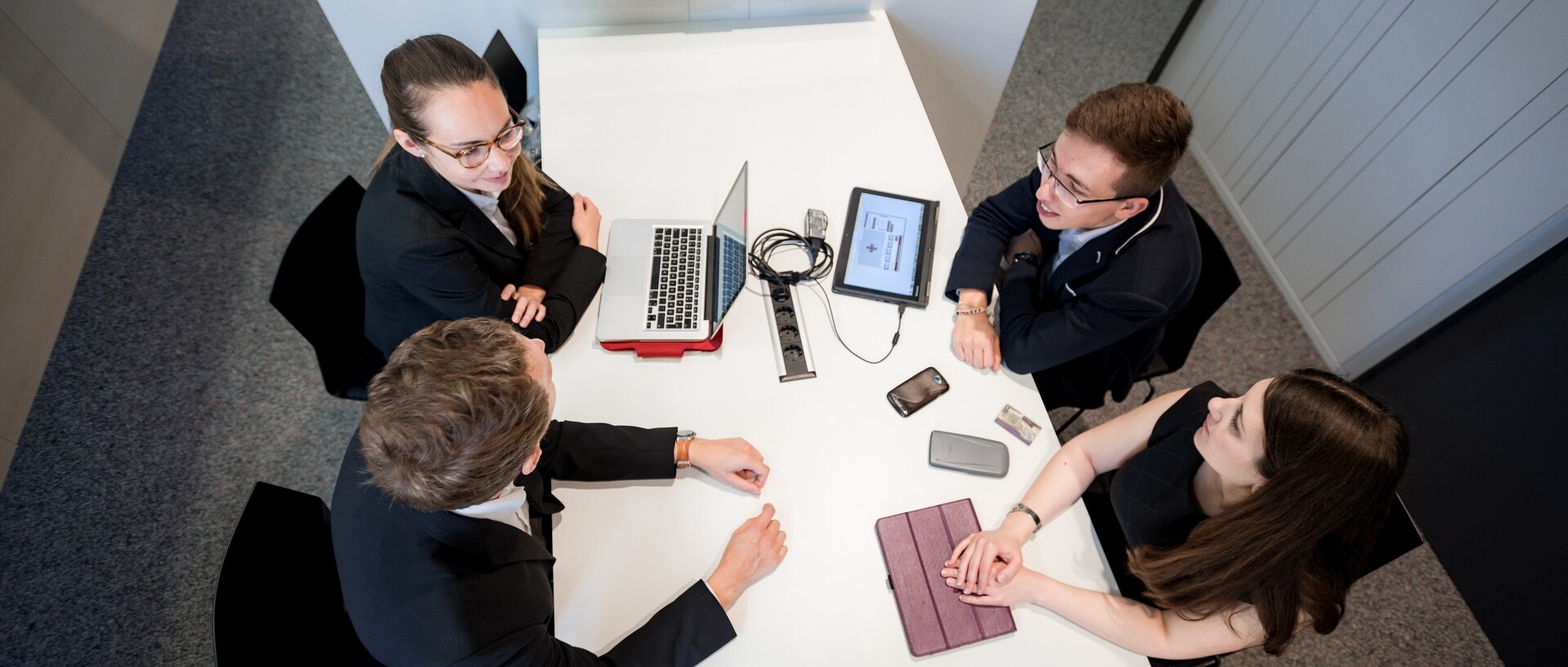 Studierende mit Lernmaterialien sitzen um Tisch