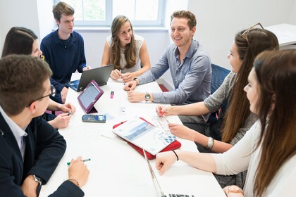 Studierende mit Laptops sitzen um einen Tisch