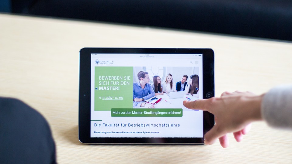 Finger zeigt auf Tablet, auf dem steht: Bewerben Sie sich für den Master! Ab 15. März - 31. Mai