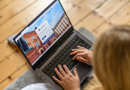 Eine Frau loggt sich auf ihrem Laptop bei einer Webseite ein.