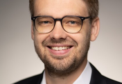 Prof. Dr. Marc Lerchenmüller hat blonde kurze Haare und einen Bart. Er trägt ein dunkles Jacket und ein weißes Hemd.