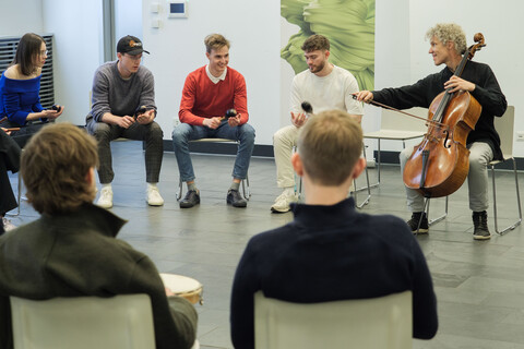 Group of people in a circle during a workshop led by a musician