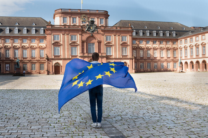 Person mit Europa-Flagge von hinten vor dem Schloss