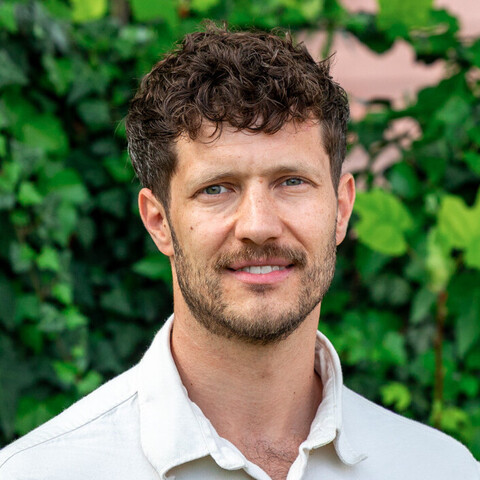 Prof. Marcel Olbert vor einer bewachsenen Gebäudefassade