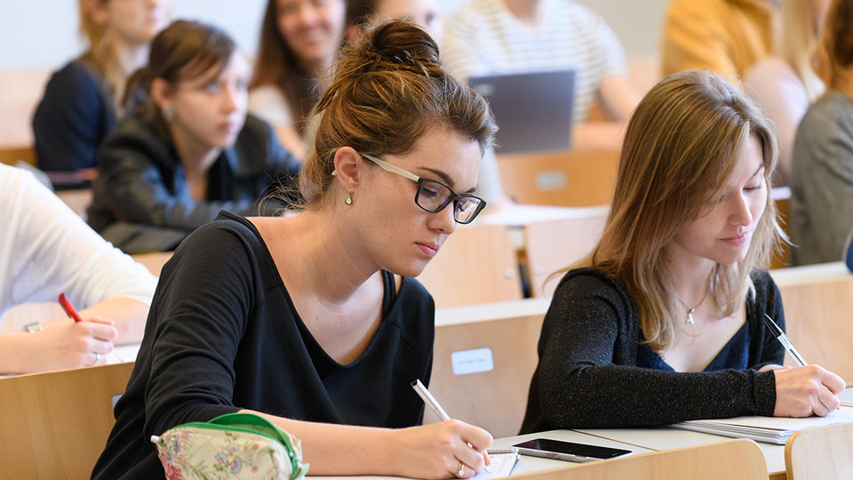 Studentinnen schreiben bei einer Vorlesung mit.