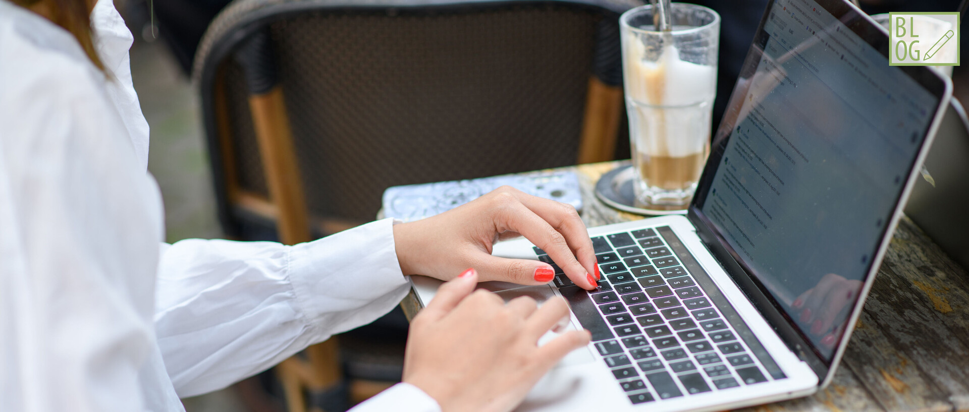 Tisch mit Eiskaffee und Laptop an dem getippt wird