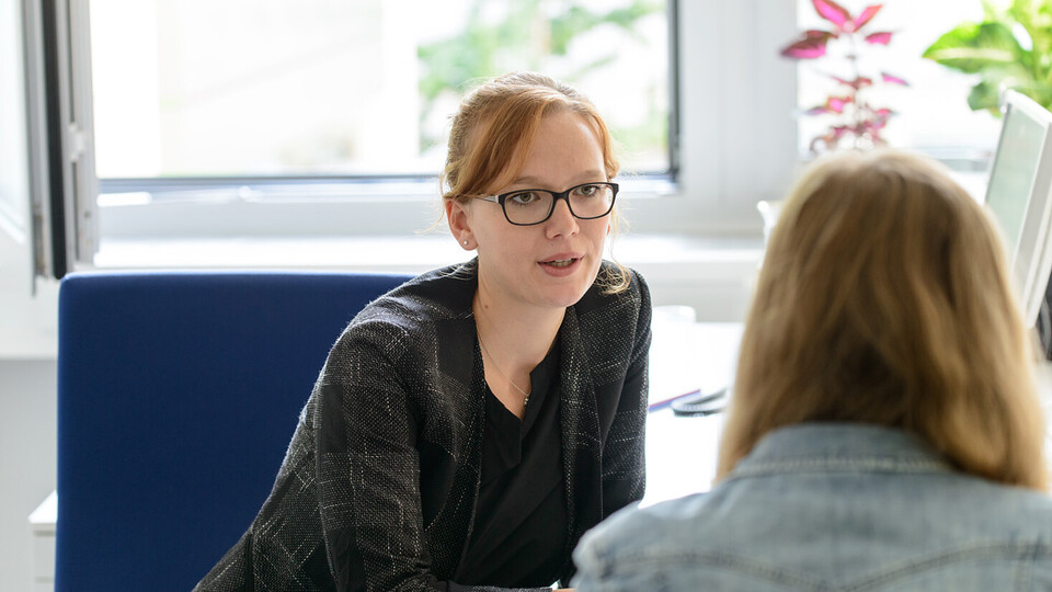 Eine Mitarbeiterin spricht im persönlichen Gespräch mit einer Studentin.