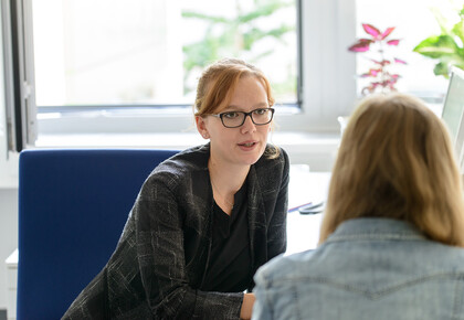 Eine Mitarbeiterin spricht im persönlichen Gespräch mit einer Studentin.