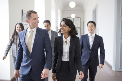 Personen in Business Kleidung laufen den Flur entlang