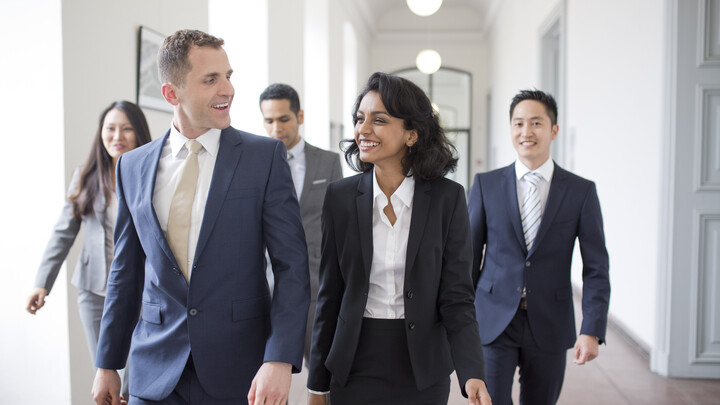 Personen in Business Kleidung laufen den Flur entlang