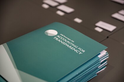 Türkisfarbene Mappen liegen auf einem schwarzen Tisch. Die Mappe haben die weiße Aufschrift "SFB/Transregio 266, Accounting for Transparency".