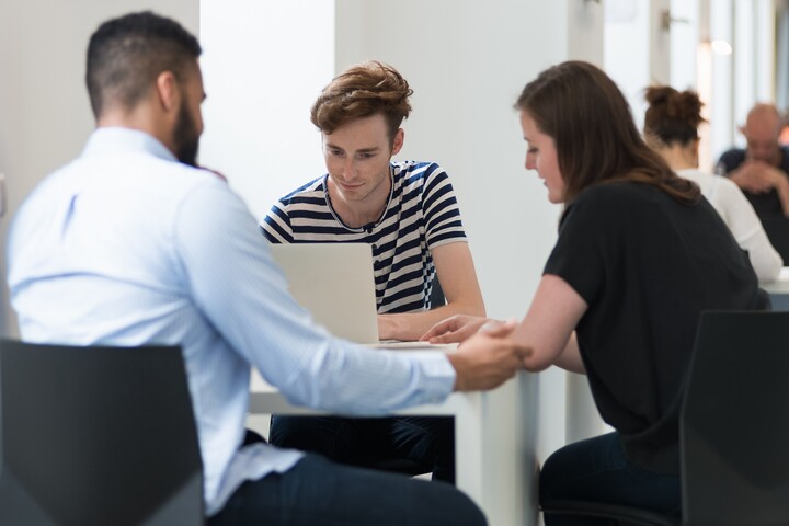 Studierende sitzen mit Lernmaterialien um Tisch