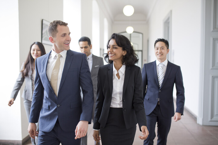 People in business attire walk along the corridor