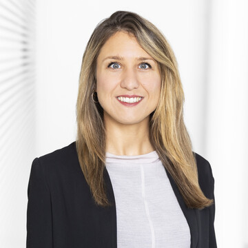 Sarah Kempe hat lange blonde Haare. Sie trägt ein helles Oberteil und einen schwarzen Blazer.