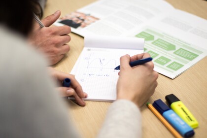 auf einem Tisch liegen Lernmaterialien, es wird eine Kurvendiskussion durchgeführt