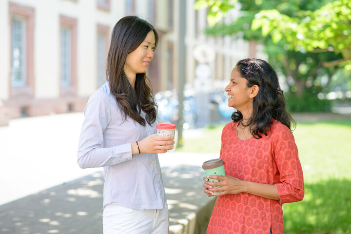 Internationale Forschende Zwei Frauen mit Kaffebechern unterhalten sich.