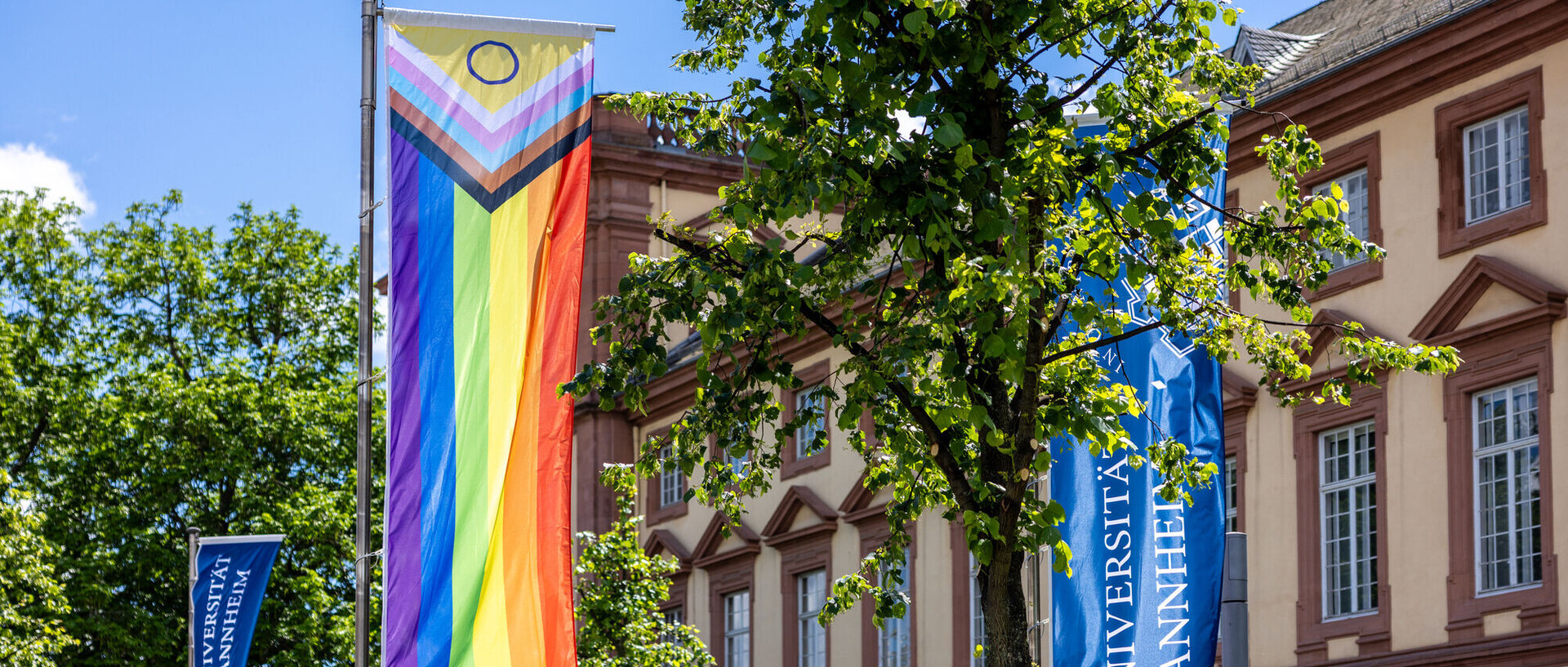 Eine Regenbogenfahne vor dem Barockschloss.